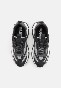 Black and gray athletic shoes with mesh panels, lace-up design, cushioned soles, and contrasting white accents. Features logo on tongue.