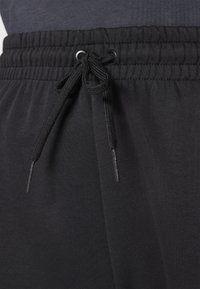 Sorte joggebukser med elastisk midje og snøring, glatt tekstur og sidelommer.