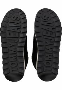Suela de goma negra con surcos profundos, con el logotipo en relieve "TOMMYJEANS", que presenta un diseño texturizado para un mejor agarre.
