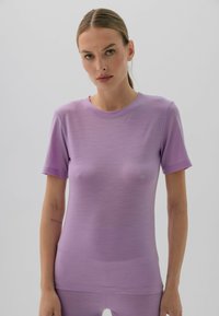 Fioletowa dopasowana koszulka, krótkie rękawy, gładka tekstura, okrągły dekolt. Prosty design bez wzorów czy akcentów.