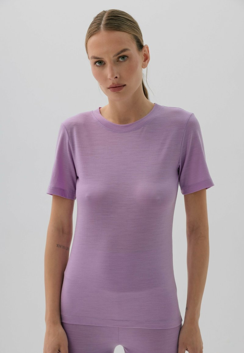 Fioletowa dopasowana koszulka, krótkie rękawy, gładka tekstura, okrągły dekolt. Prosty design bez wzorów czy akcentów.