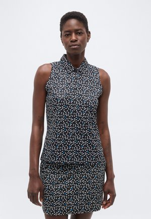 Nő ujjatlan fekete ruhában, fehér és kék levelekkel díszítve, világosszürke egyszínű háttér előtt áll.