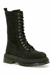 Botas de combate de ante negro con un cierre de cordones en la parte delantera, ojales plateados y una suela de goma texturizada y gruesa. El diseño presenta un perfil hasta la rodilla.