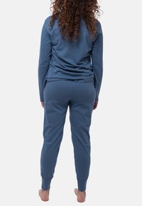 Niebieski dwu-elementowy zestaw odzieży domowej wykonany z miękkiego materiału. Górna część ma luźny krój z długimi rękawami, a spodnie mają wykończone mankiety.