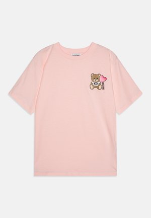 Camiseta de algodón rosa con mangas cortas, que presenta un oso de peluche impreso con un corazón y la palabra "TOY" en el lado izquierdo del pecho.