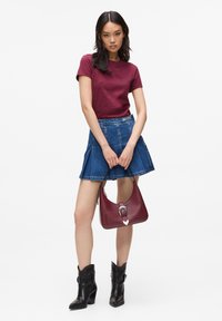 Burgundské tričko, džínová sukně s volánovým zakončením, černé kotníkové boty a burgundská kabelka se stříbrnou sponou. Jednoduchý, casual outfit.