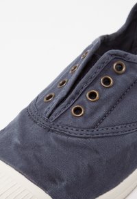 Mornarski platneni teniški čevlji z mesingastimi okovji, šivanjem podrobnosti in teksturirano zgornjimi deli. Belega gumijastega podplata z teksturiranim oprijemom.