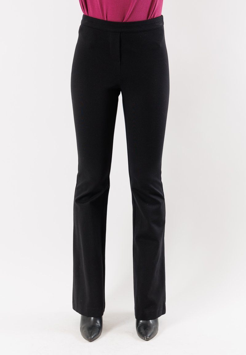 Pantaloni neri a zampa d'elefante in tessuto liscio. Presentano una vita aderente e cuciture sottili. Abbinati a scarpe nere con punta a stiletto.