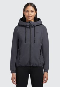 Veste à capuche grise, légère, avec une fermeture éclair à l'avant, des poignets élastiques et deux poches zippées. Présente une texture de tissu lisse et un branding discret.