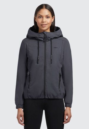 Veste à capuche grise, légère, avec une fermeture éclair à l'avant, des poignets élastiques et deux poches zippées. Présente une texture de tissu lisse et un branding discret.