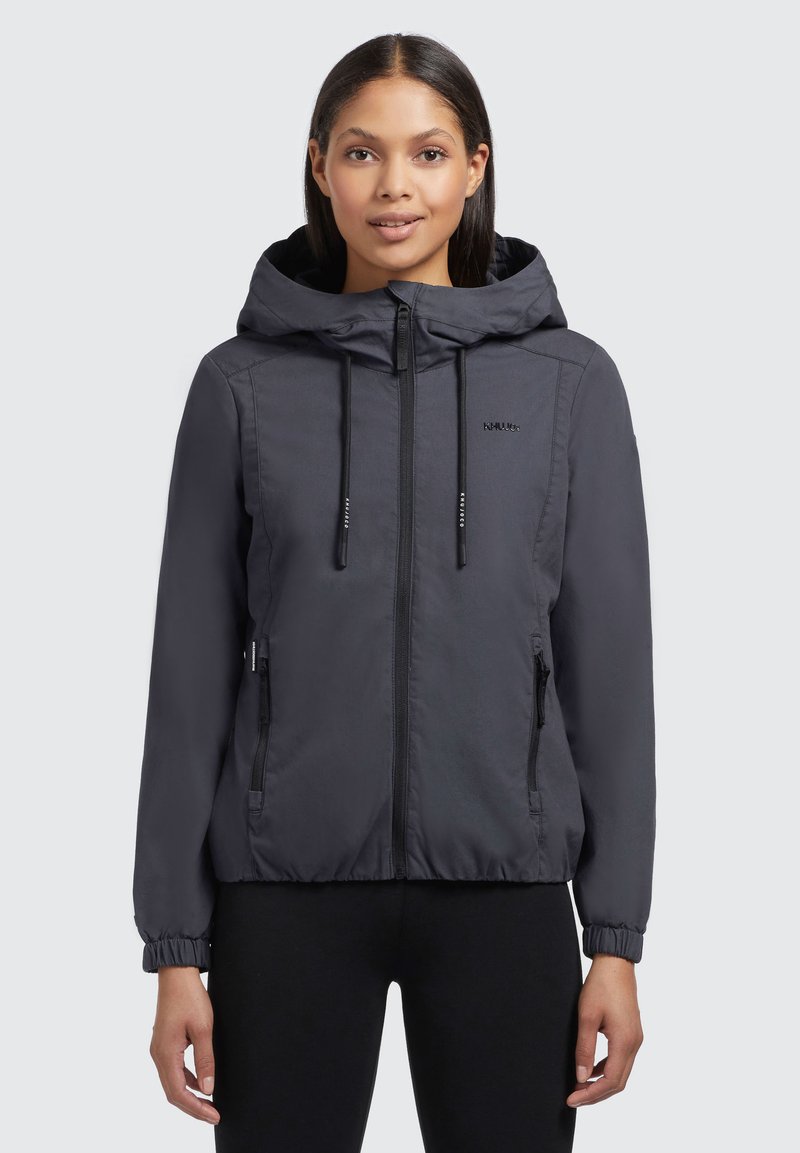 Veste à capuche grise, légère, avec une fermeture éclair à l'avant, des poignets élastiques et deux poches zippées. Présente une texture de tissu lisse et un branding discret.