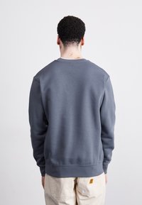 Gray crewneck sweatshirt with a soft texture, ribbed cuffs and hem, and a relaxed fit. No visible branding or patterns.