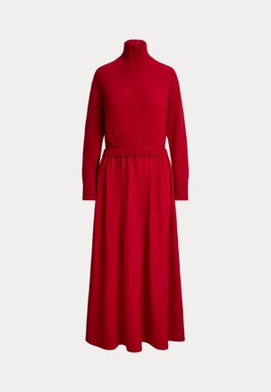 Une longue robe rouge avec un haut en maille côtelée à col montant, des manches longues, une taille ajustée et une jupe fluide, présentée sur un fond uni.