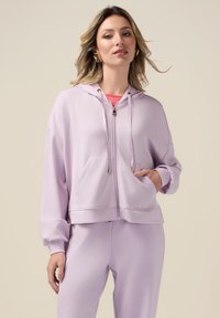 Felpa zip-up lavanda realizzata in tessuto morbido con design cropped, cappuccio con cordino e tasche anteriori. Dettagli in metallo color oro.