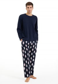 Granatowa bluzka z długim rękawem zestawiona z wzorzastymi spodniami, na których znajdują się różowe i białe drzewa na ciemnym tle. Miękki materiał bawełniany.