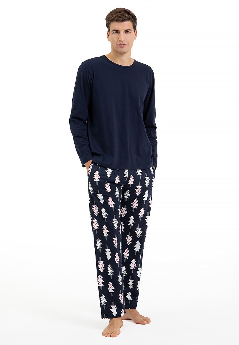 Granatowa bluzka z długim rękawem zestawiona z wzorzastymi spodniami, na których znajdują się różowe i białe drzewa na ciemnym tle. Miękki materiał bawełniany.
