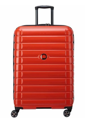 Valigia rigida rossa con scanalature orizzontali, manico telescopico e quattro ruote girevoli. Presenta una cerniera nera e dettagli con logo.