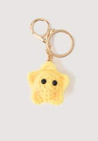 Yellow crocheted star with black eyes attached to gold keychain ring and clasp on white background.