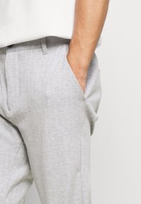 Gray striped trousers with a smooth texture, featuring side pockets and a straight-leg design. The waistband includes a loop for a belt.