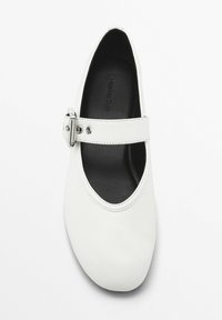 Scarpa piatta in pelle bianca con punta arrotondata, cinturino alla caviglia con fibbia argentata e soletta nera imbottita. Design semplice privo di motivi.