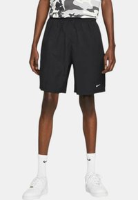 Black athletic shorts with an elastic waistband, made of lightweight material, featuring a small white Nike logo on the lower left side.