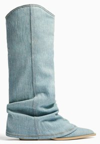 Denim Stiefelette mit schlabbriger Form, hellblauer Farbe, spitzer Zehenpartie und sichtbaren Nähdetails entlang der Nähte.