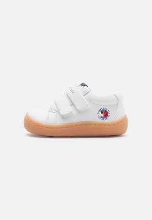 White toddler sneaker with two Velcro straps, beige rubber sole, and circular Tommy Hilfiger Los Angeles logo on the side.