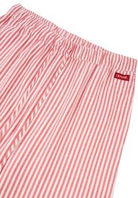 Røde og hvite stripete shorts i stoff med elastisk midjebånd og en liten rød etikett sydd på høyre side. Myk tekstur og avslappet design.