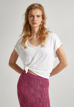 Top blanco de manga corta, holgado y atado en la cintura, combinado con una falda texturizada de color rosa intenso con un patrón de encaje y una cinturilla acanalada.