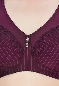 Bordeauxfarvet bh med tekstureret stof, blonder og lodrette striber. Har en dekorativ midterlås med små rhinsten.