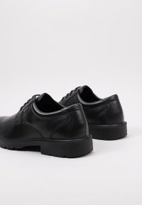 Chaussures en cuir noir avec une texture lisse, bout rond, design à lacets et semelle en caoutchouc robuste. Présente un minimum de coutures et d'accents.