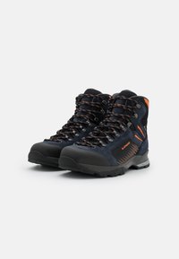 Hochschuh-Wanderstiefel aus dunkelblauem Wildleder mit schwarzer Gummikappe, orangen Akzenten und mehrfarbigen Schnürsenkeln. Strukturiertes, profilierte Sohle.