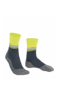 Szare i ciemnoniebieskie skarpetki z jaskrawym żółtym mankietem i trzema poziomymi paskami. Są wyeksponowane obok siebie na białym tle.