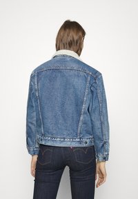 Jeansjacka i ljusblått med vit fårskinnskrage, klassisk skärning, knäppta ärmslut och två bakfickor. Mjuk textur med en blekt finish.