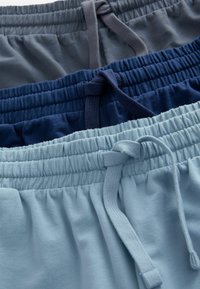 Tres pares de pantalones cortos con cintura elástica en diferentes tonalidades: gris oscuro, azul marino y azul claro, con cordones y texturas suaves.