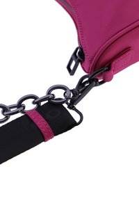 Bolso de hombro de nailon rosa con una textura suave, que presenta una correa negra en forma de cadena y accesorios metálicos. Cierre de cremallera visible.