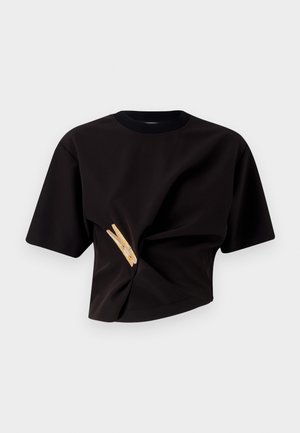 Camiseta negra recortada de manga corta, con un diseño retorcido y un adorno decorativo en forma de pinza de ropa amarilla en el frente.