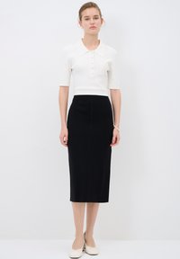 Weißes geripptes Cropped-Top mit Kragen und Knöpfen, kombiniert mit einem langen schwarzen Bleistiftrock. Strukturierten Stoff, minimalistisches Design, neutrale Farben.