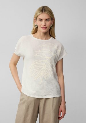 T-shirt blanc léger à manches courtes et coupe décontractée. Présente un motif de feuille texturé en jaune pâle sur le devant.