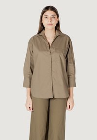Camicia beige con bottoni, colletto, maniche lunghe, taschino sul petto e taglio dritto, realizzata in tessuto morbido e leggero.
