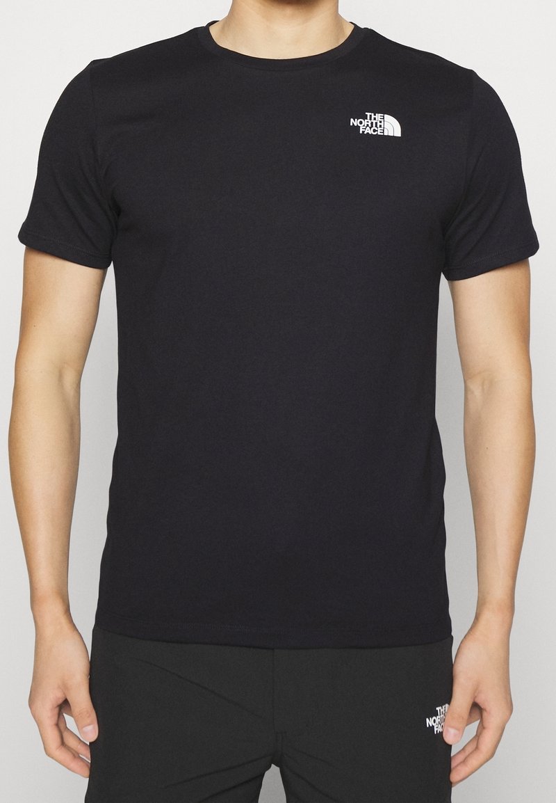 Camiseta de algodón negra, de manga corta, con cuello redondo, presenta un pequeño logo blanco en el lado izquierdo del pecho. Textura suave, diseño ajustado.