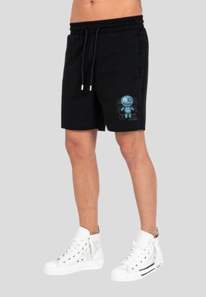Gambe maschili che indossano pantaloncini neri con coulisse, con una toppa a cartone animato blu e scarpe da ginnastica alte bianche su uno sfondo semplice.