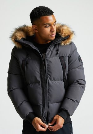 Dunkelgraue Daunenjacke mit einem mit Fell gefütterten Kapuzen, Reißverschluss vorne und schwarzen Akzenten. Verfügt über elastische Bündchen und seitliche Taschen.
