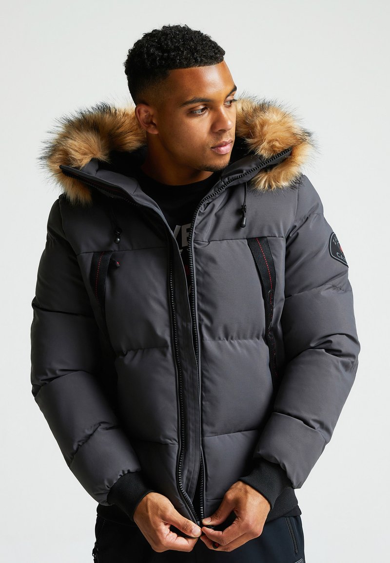 Tumesinine puhvjak Siga, millel on karusnaha voodriga kapuuts, tõmblukuga esiosa ja mustad detailid. Omab elastseid mansette ja küljetaskuid.