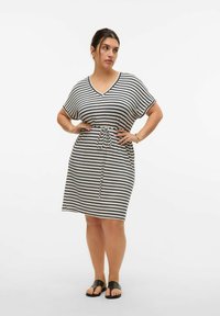 Gestreepte jurk in crème en marineblauw met een V-hals, korte mouwen en een trekkoord in de taille. Zacht materiaal met een ontspannen pasvorm. Gemaakt met zwarte sandalen.