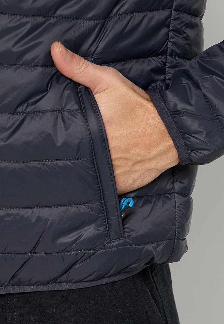 Giacca puffer blu navy con design trapuntato, tasca laterale e zip blu. Presenta una texture liscia e polsini aderenti.
