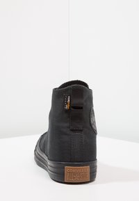 Sneaker alta nera in tela con suola in gomma, dotata di un pratico passante sul retro e di una targhetta loggata testurizzata. Design resistente e versatile.