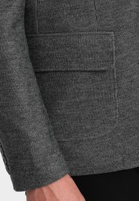 Szary teksturowany marynarka w subtelny wzór kratki, z naszywaną kieszenią i dopasowanym mankietem z ozdobnymi guzikami.