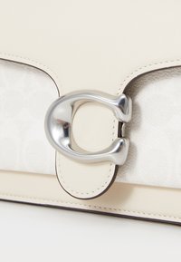 Cream leather handbag with a textured white fabric section. Features a silver clasp and contrasting dark stitching along the edges.