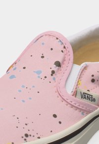 Ροζ πάνινο παπούτσι Vans με σχέδιο πολύχρωμων πιτσιλιών μπογιάς και λευκή λαστιχένια σόλα, που δείχνει το μπροστινό πάνω μέρος και την ετικέτα με το λογότυπο.